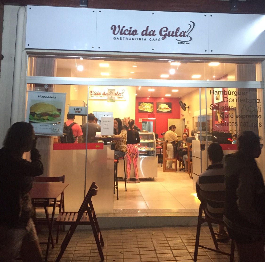 Fachada iluminada à noite do Vício da Gula Gastronomia Café no centro de Bonito MS, local popular para lanches e refeições rápidas.