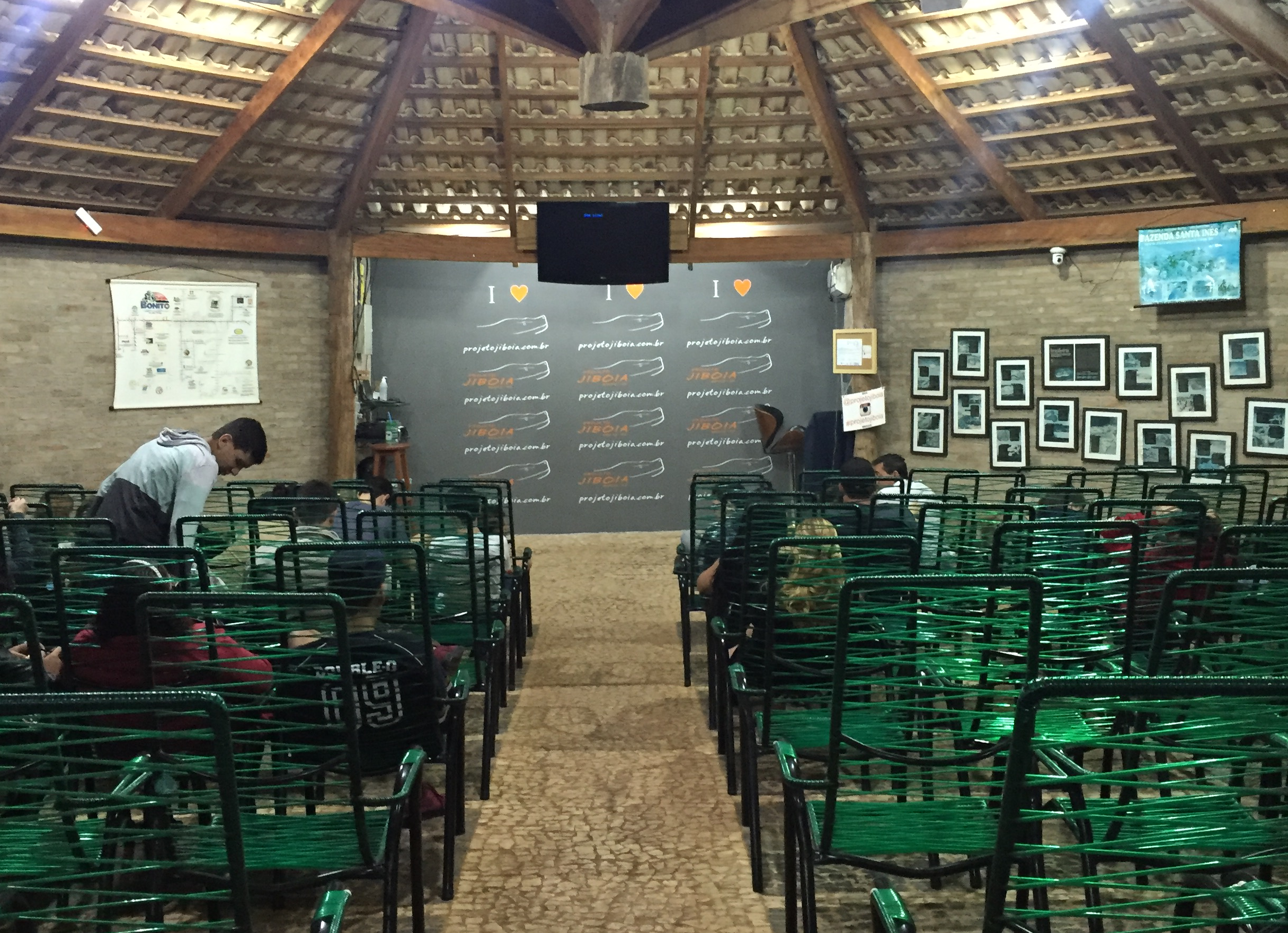 Interior do auditório do Projeto Jiboia em Bonito MS, com cadeiras verdes organizadas e palco para apresentação de educação ambiental sobre serpentes.