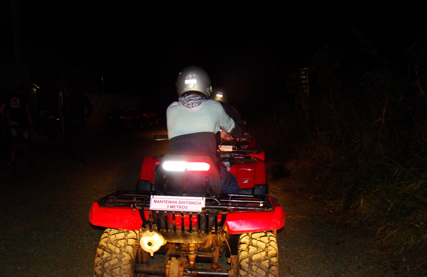 Turistas pilotando quadriciclos durante passeio noturno em trilha de aventura em Bonito MS.