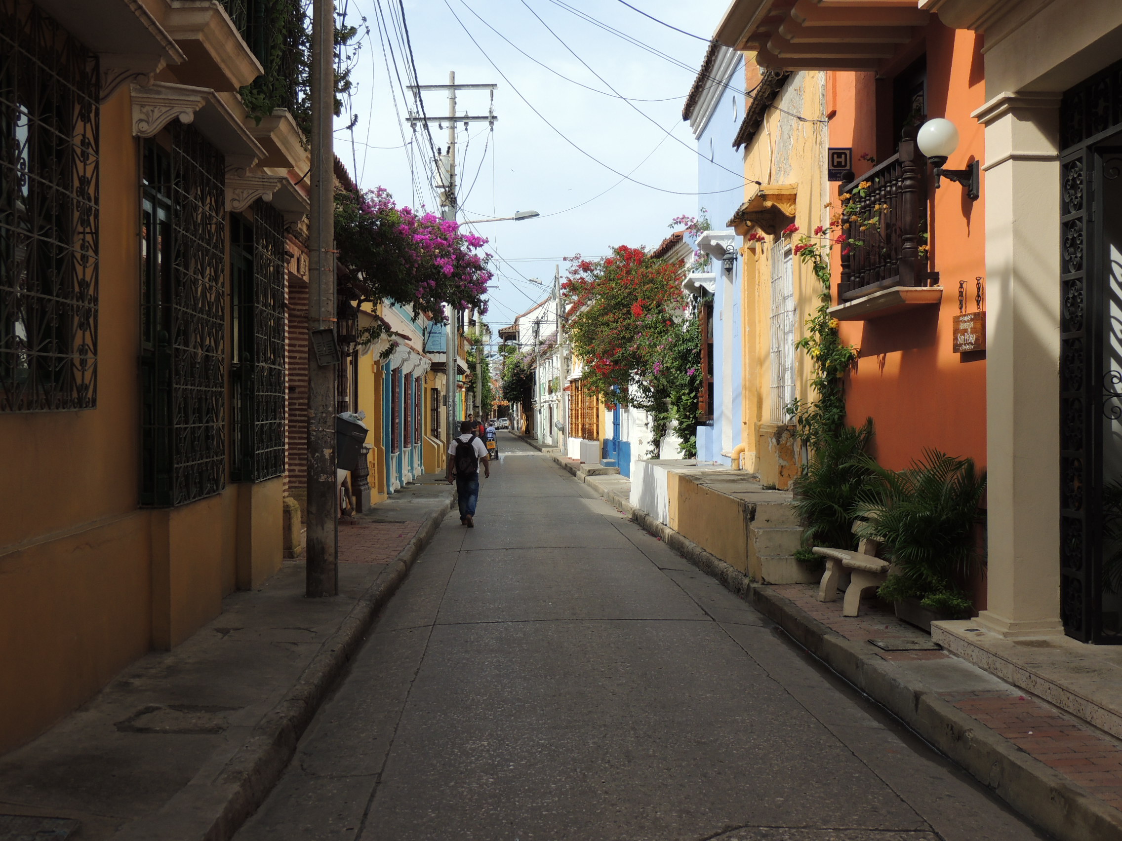 Rua estreita na Cidade Murada de Cartagena com casas de arquitetura colonial colorida, varandas e flores primavera.