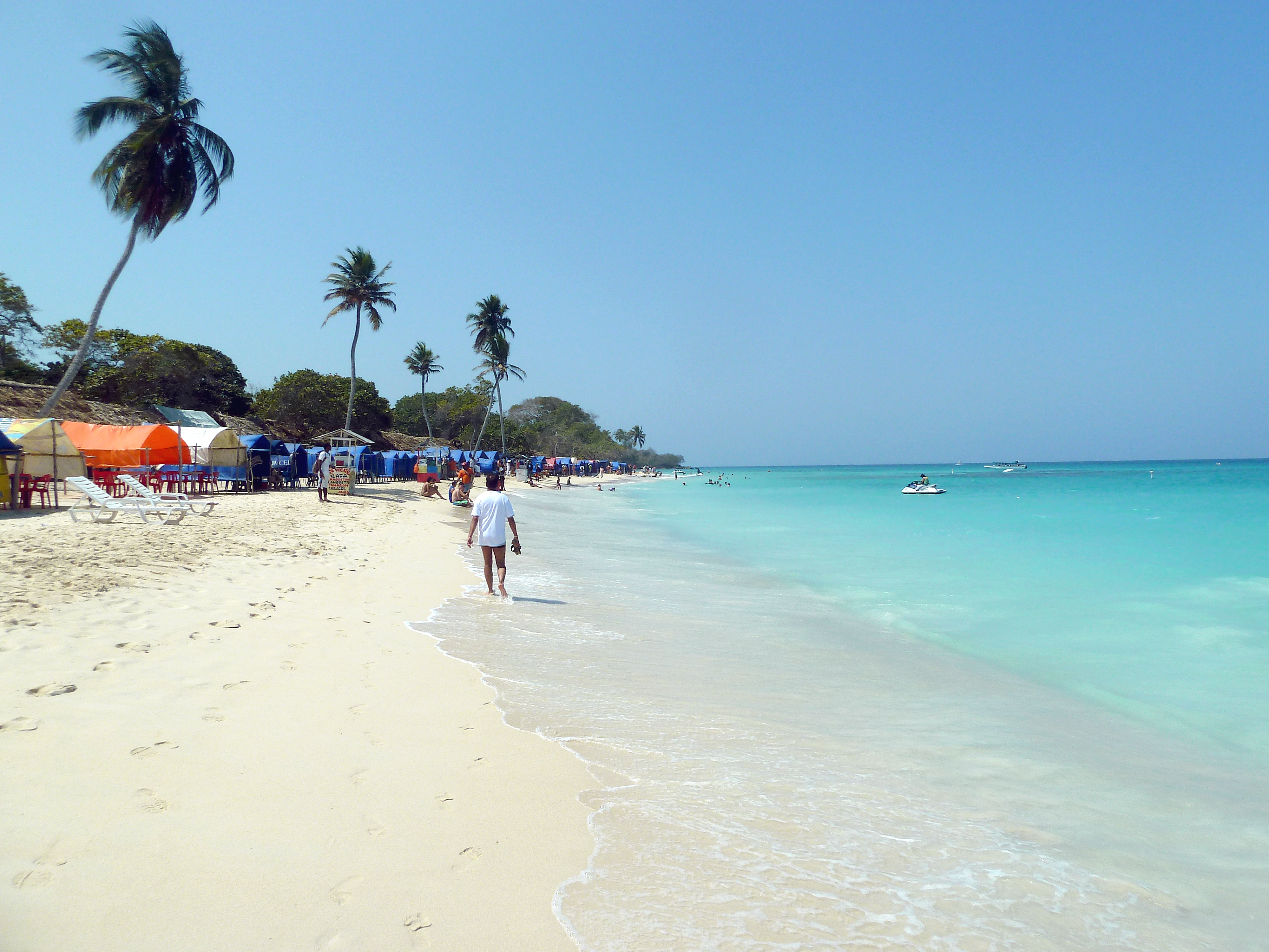 Paisagem da Playa Blanca na Isla Barú em Cartagena, com areia branca, coqueiros e mar do Caribe azul cristalino.