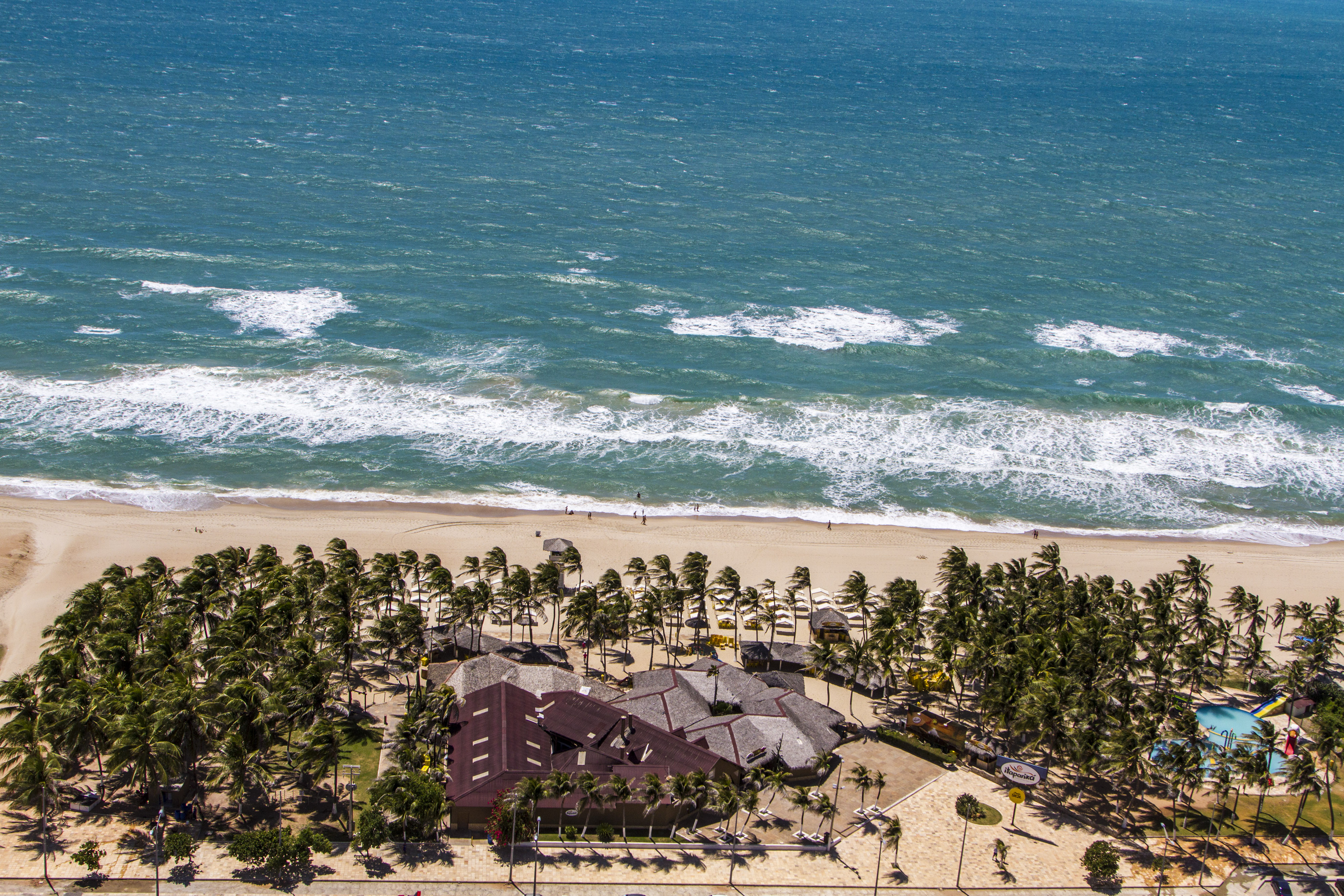 Vista aérea da Praia do Futuro em Fortaleza, Ceará, mostrando a mega barraca Chico do Caranguejo, coqueiros e o mar.
