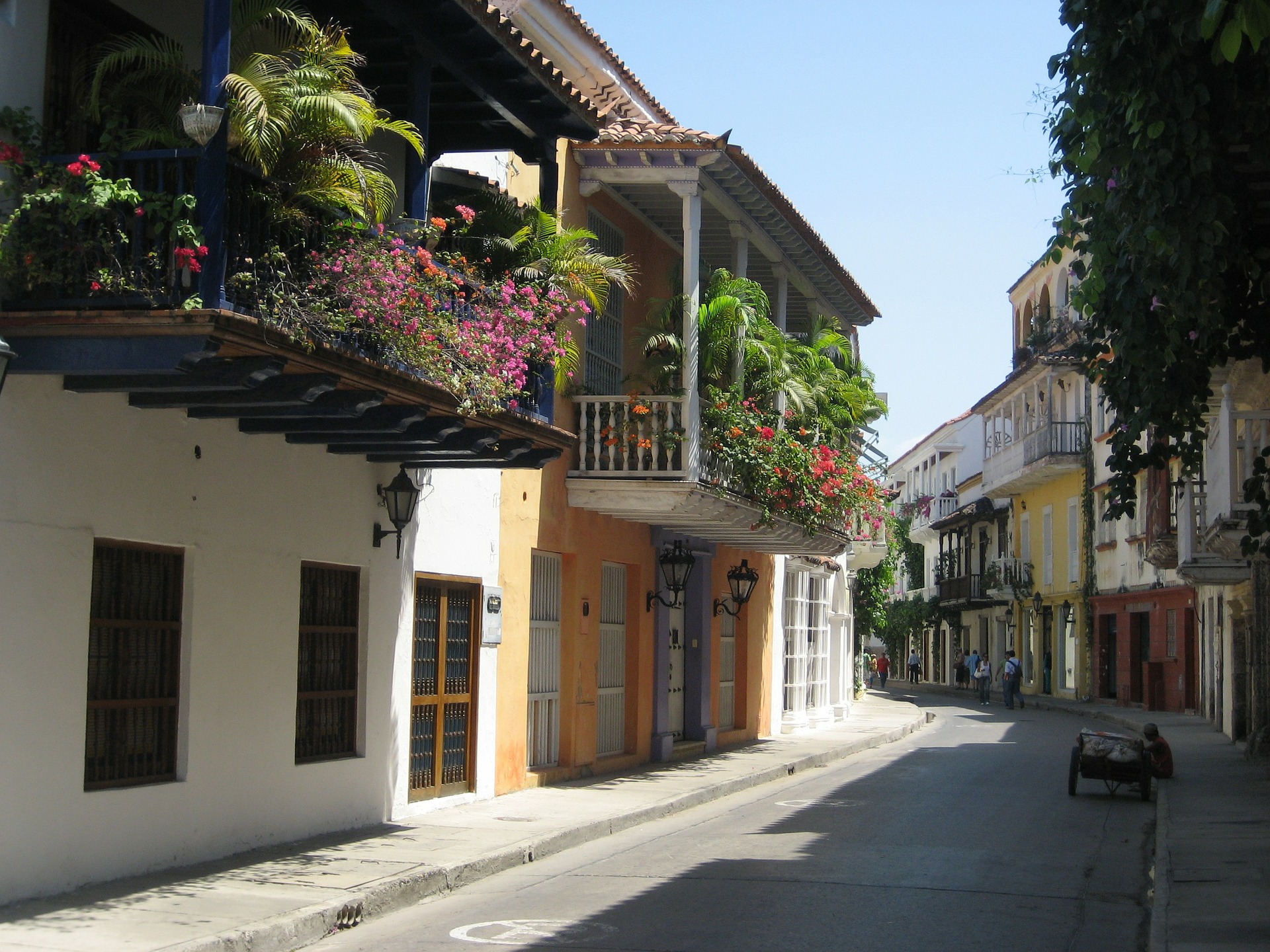 Rua pitoresca no centro histórico de Cartagena com arquitetura colonial colorida, varandas floridas e atmosfera turística.