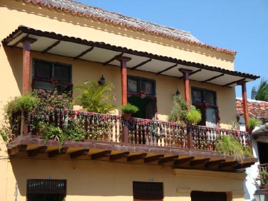 Varanda colonial de madeira decorada com flores coloridas na fachada de um prédio amarelo na Cidade Amuralhada de Cartagena.
