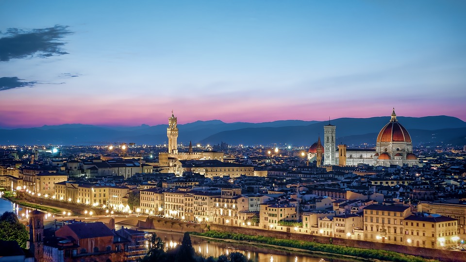 Vista panorâmica do skyline de Florença ao entardecer, com destaque para a cúpula do Duomo e a torre do Palazzo Vecchio iluminados sobre a cidade.Wikimedia Commons