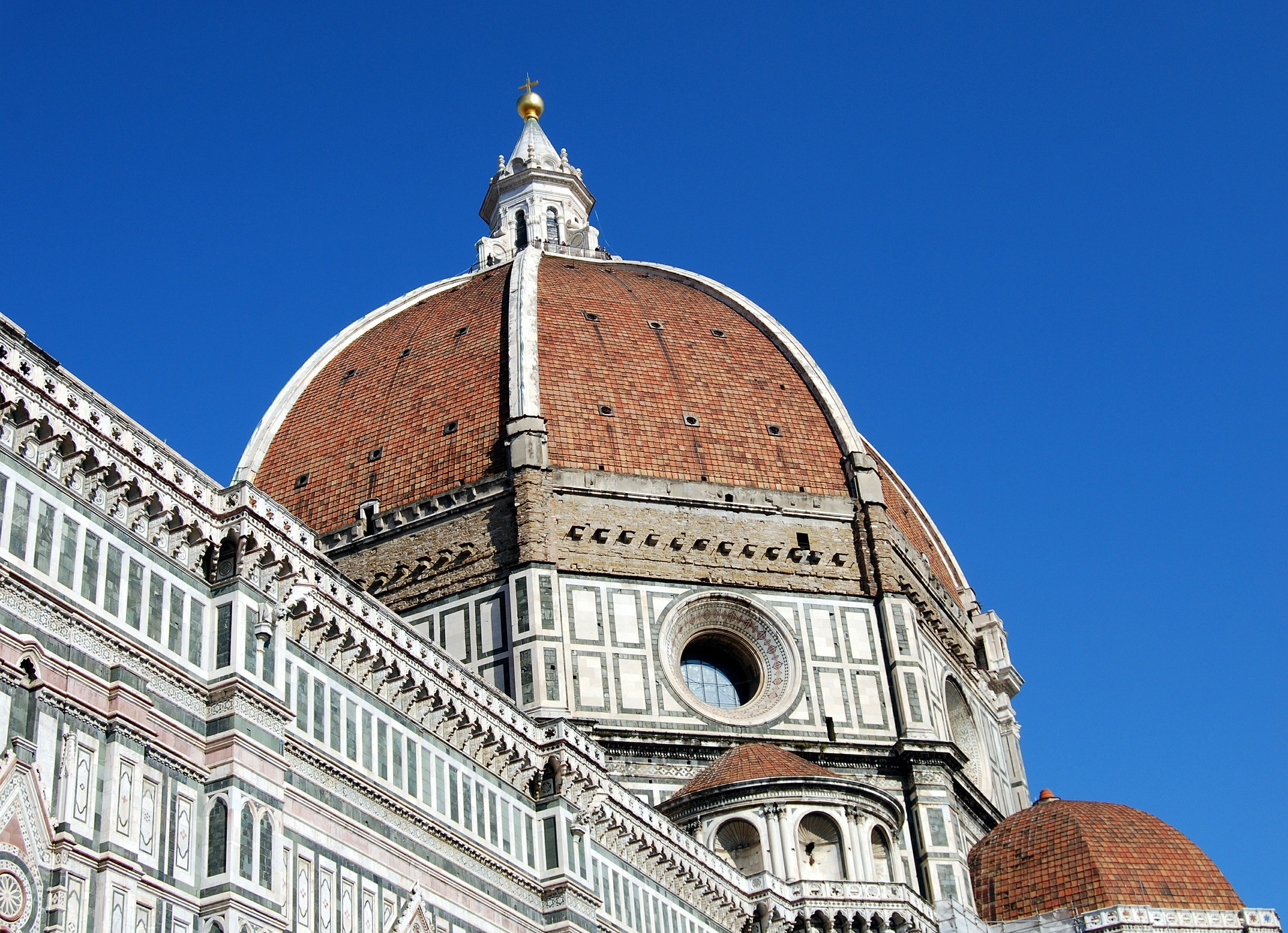 Detalhe em close da Cúpula de Brunelleschi na Catedral de Santa Maria del Fiore (Duomo), destacando as telhas vermelhas e o mármore branco.
