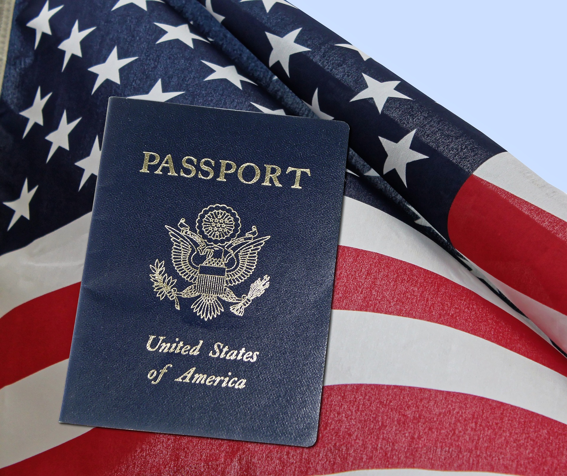 Passaporte dos Estados Unidos sobre a bandeira americana, destacando a importância da verificação de documentos e vistos na organização de viagens internacionais.