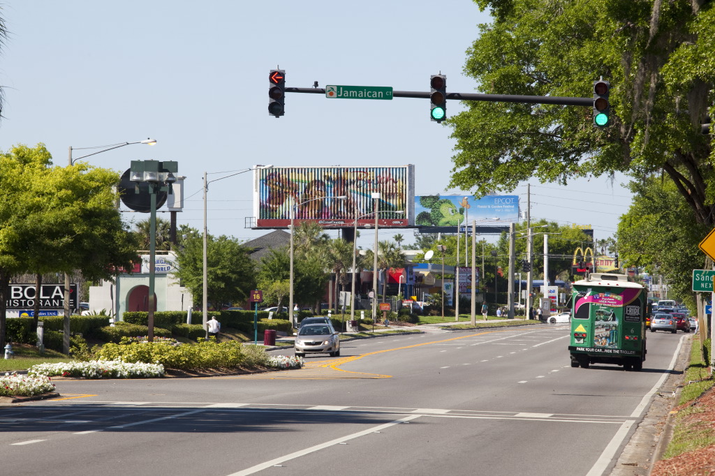 Vista da International Drive (I-Drive) em Orlando com placas de sinalização turística e o ônibus I-Ride Trolley.