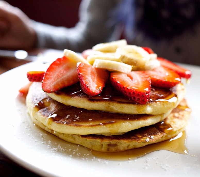 Café da manhã típico americano com torre de panquecas, morangos e bananas em restaurante de Orlando.