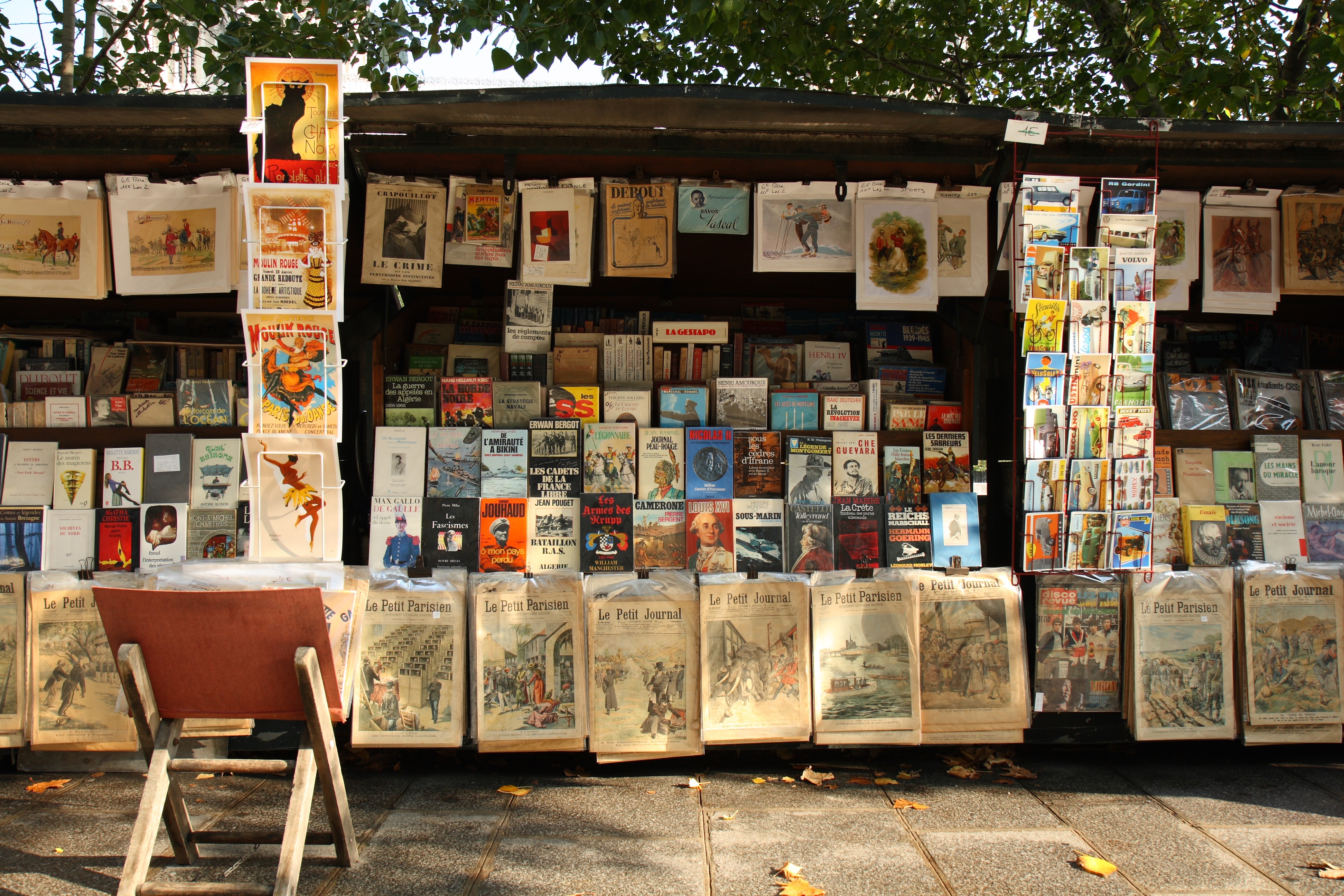 Banca verde tradicional de um Bouquiniste às margens do Rio Sena em Paris, exibindo livros antigos, pôsteres vintage e arte para turistas.