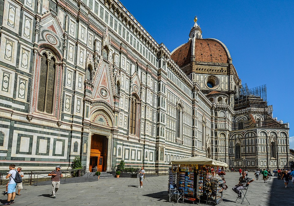 Fachada detalhada e cúpula de Brunelleschi da Catedral de Santa Maria del Fiore, o Duomo de Florença, sob céu azul.