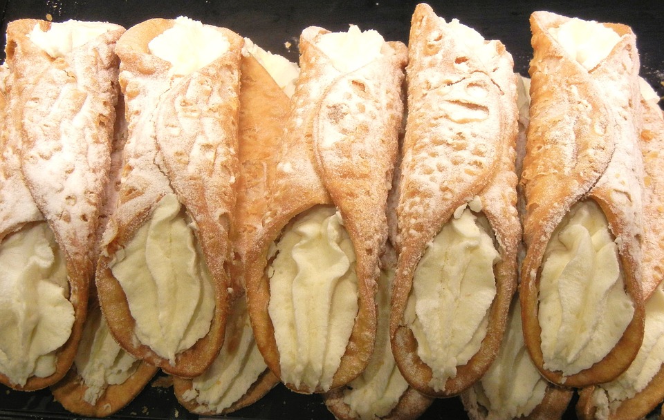 Close-up de vários cannoli, doces italianos tradicionais recheados com creme de ricota e polvilhados com açúcar.